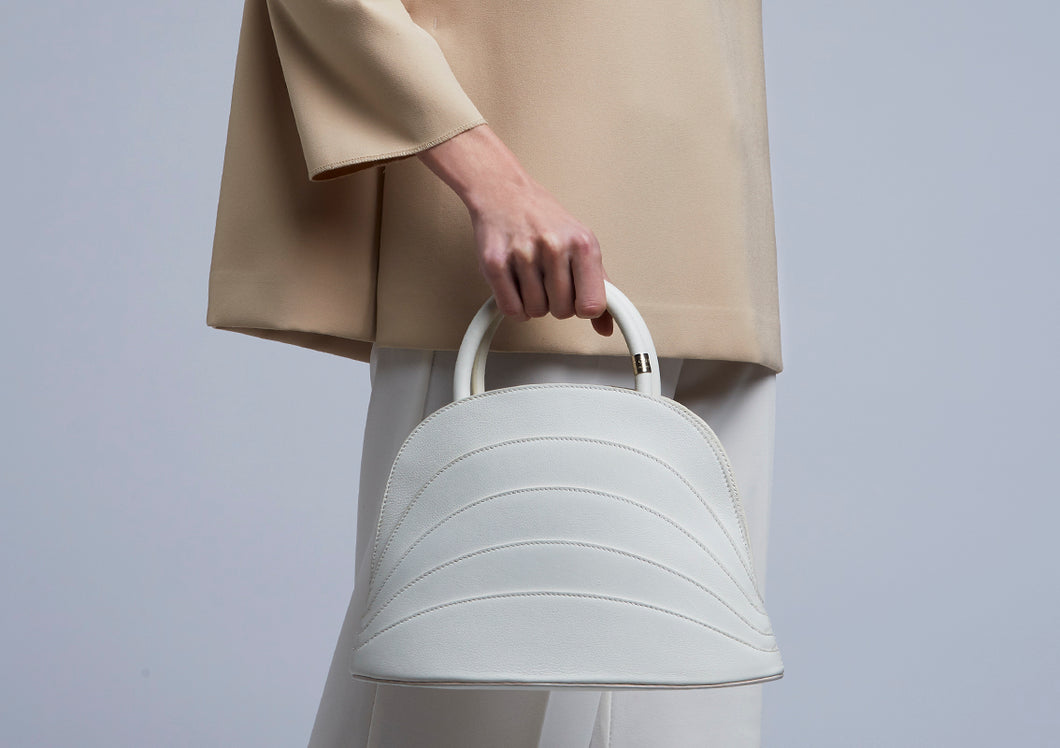 The model wears a Gabo Guzzo Millefoglie J handbag in white calfskin and gold plated hardware. One-of-a-kind creation embellished with fine jewellery and handcrafted in Italy.