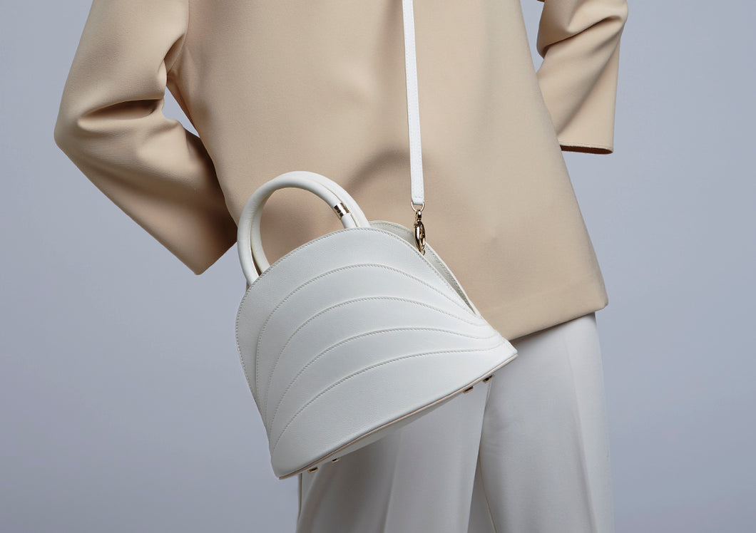 The model wears a Gabo Guzzo Millefoglie J handbag in white calfskin and gold plated hardware. One-of-a-kind creation embellished with fine jewellery and handcrafted in Italy.